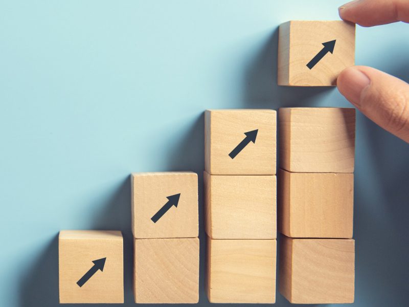 Business concept growth success process, Close up Woman hand arranging wood block stacking as step stair on paper blue background, copy space.